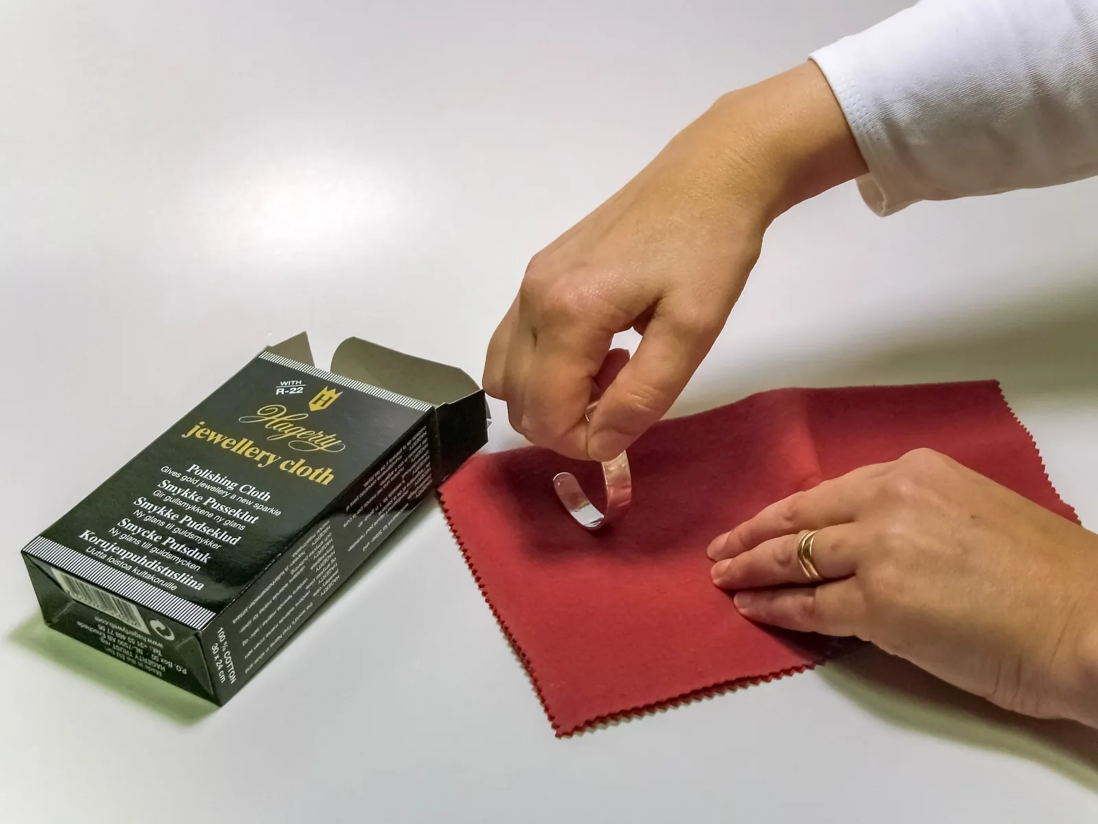 Cleaning silver jewelry. Last, use a cloth containing some polishing agent to polish the clean piece. There are special cloths, or a piece of fabric dipped in some combined silver polish can be used. When the jewellery is clean and de-oxidized, polishing the surface will be easier and there is no risk of small remaning grains of sand or dirt to scratch the surface. Studio photography in Sophies Silver jewellery workshop in Visby, Gotland, Sweden.