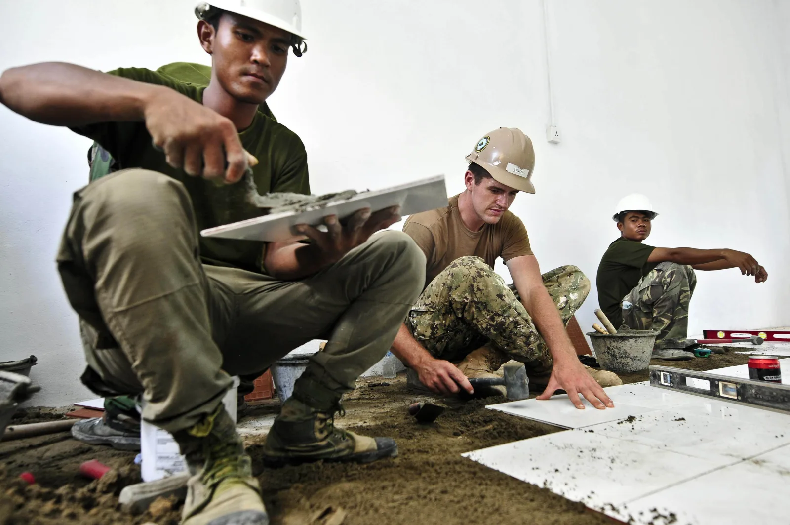 U.S. Navy Equipment Operator Constructionman Aaron Lynch, center, lays floor tile with Cambodian soldiers during an engineering civic action project at Kampung Kreng Health Center Aug. 6, 2012 in Sihanoukville, Cambodia, during Pacific Partnership 2012. Pacific Partnership is an annual deployment of forces designed to strengthen maritime and humanitarian partnerships during disaster relief operations, while providing humanitarian, medical, dental and engineering assistance to nations of the Pacific.
(DoD photo by Kristopher Radder, U.S. Navy/Released)
