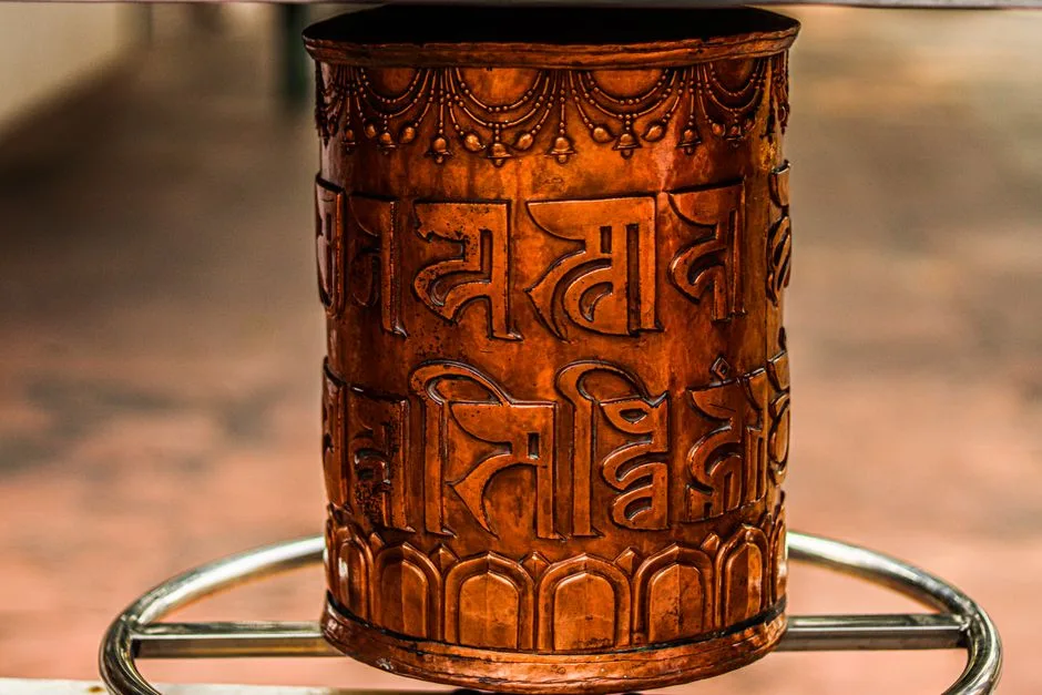 Close-up of an ornate bronze cylinder with intricate relief design and script detail.