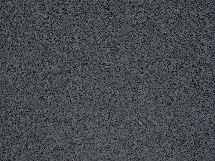 Detailed view of a gray synthetic doormat showcasing its fiber texture.