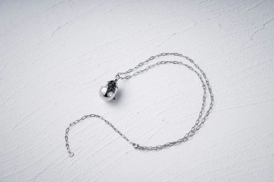 Elegant minimalist silver chain necklace with unique pendant on textured white background, perfect for fashion designs.