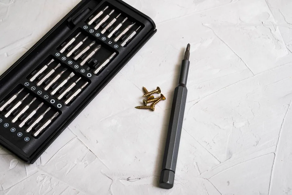 Close-up of a precision screwdriver kit with various bits and screws on a light textured background.