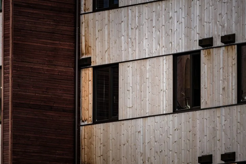 Close-up of a modern building facade with alternating wooden panels and windows.