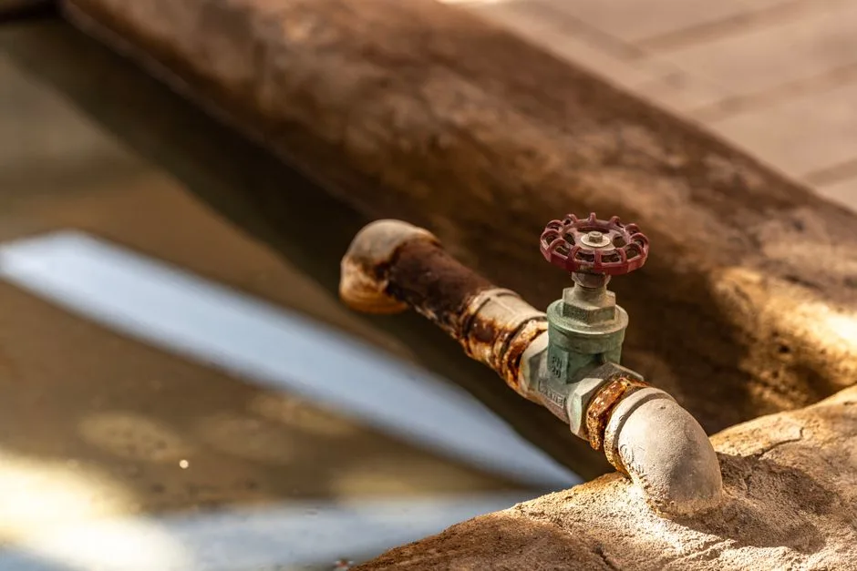 Close-up of a rusty water valve with reflections in a Dubai setting, highlighting decay and water themes.