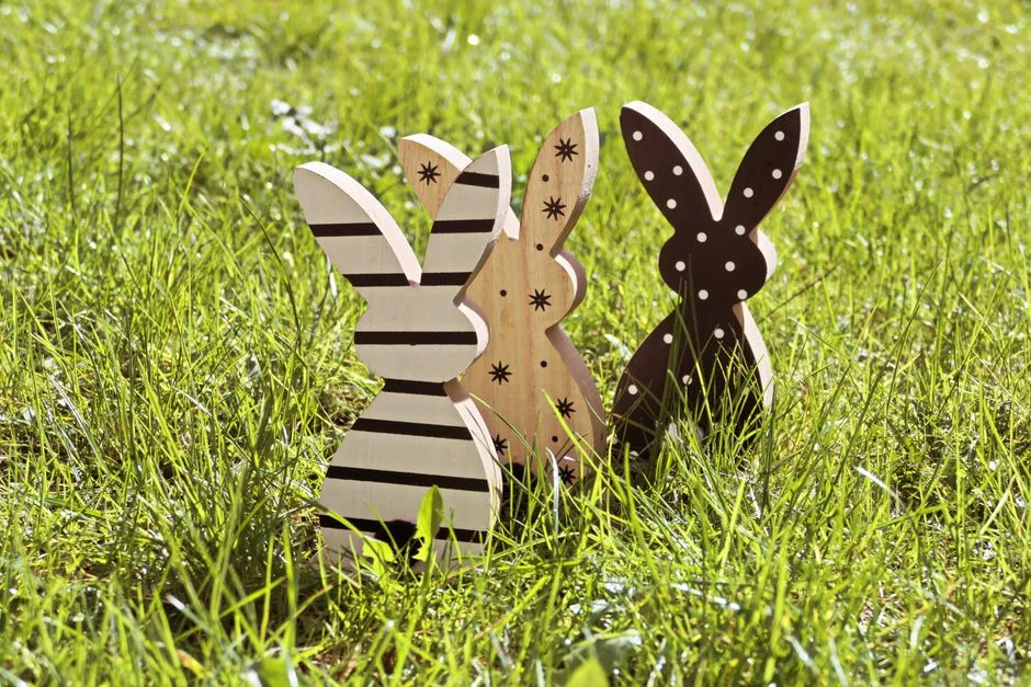 Three wooden bunny decorations on green grass, perfect for Easter themes.