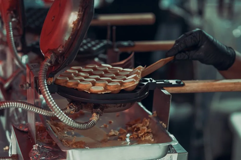 Close-up of bubble waffles cooking in a professional waffle maker at a street market.