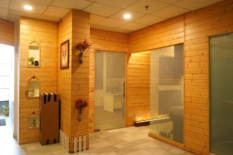A cozy office space with wooden wall panels, illuminated by warm lighting and featuring modern glass doors.