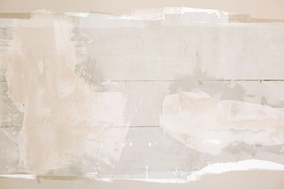 Close-up of an unfinished wall showing plaster and paint textures in a home renovation.