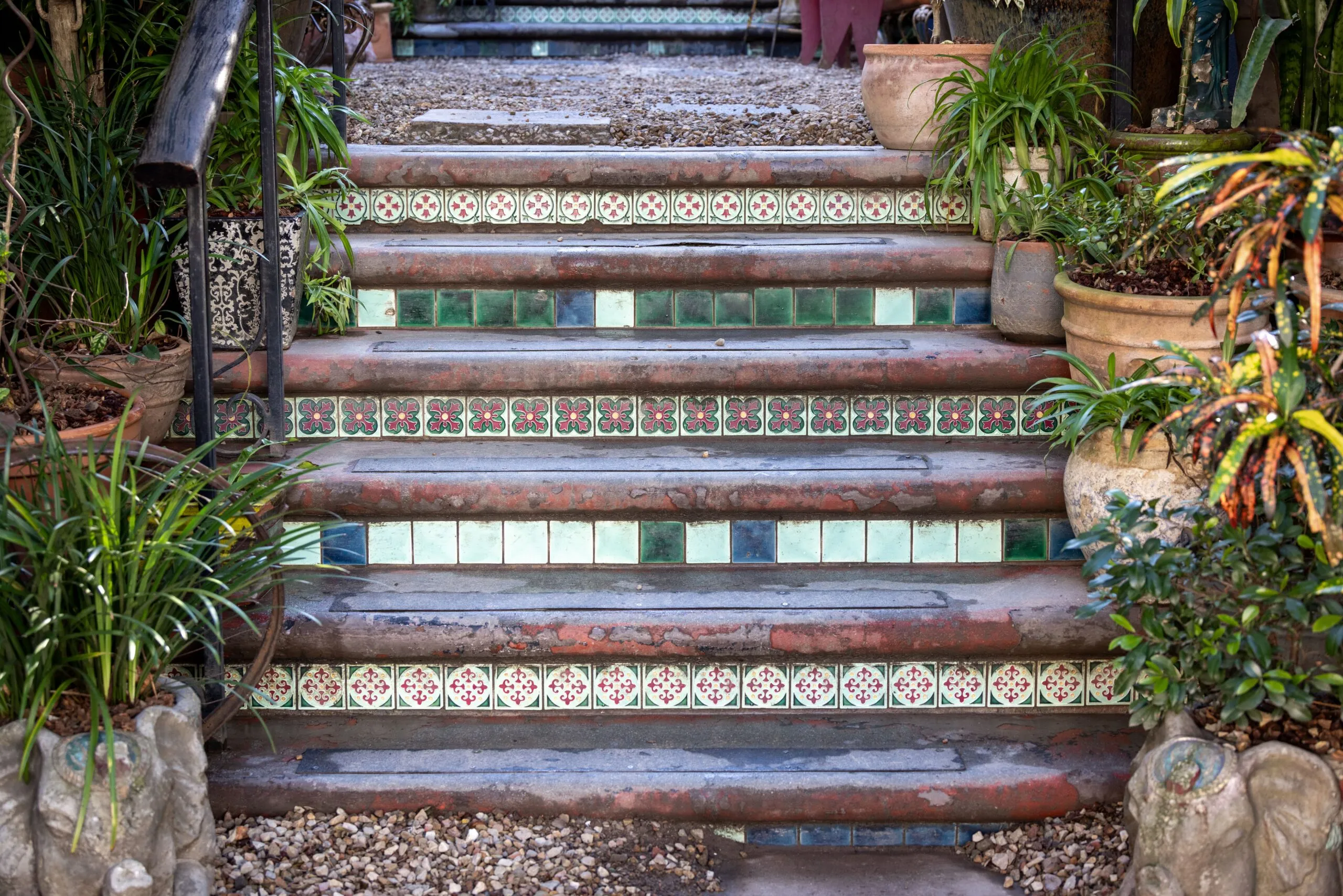 Decorative garden stairs adorned with colorful tiles and surrounded by lush potted plants.