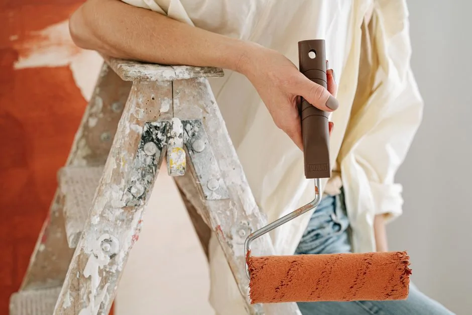 A close-up of a person using a roller to paint a wall during renovation.