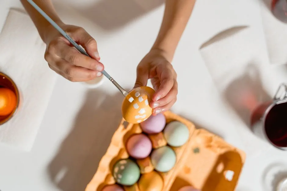 Hands painting Easter eggs with a brush, showcasing colorful designs and creativity.