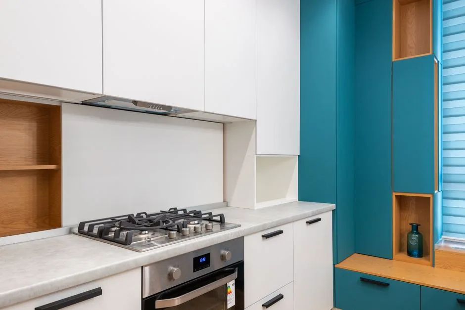 White cabinet with gas stove and empty shelves against jalousie in contemporary light house