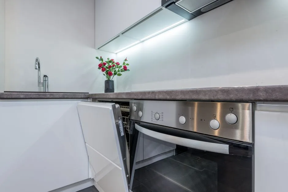 Sleek kitchen interior featuring an open dishwasher and vibrant flowers on the counter.