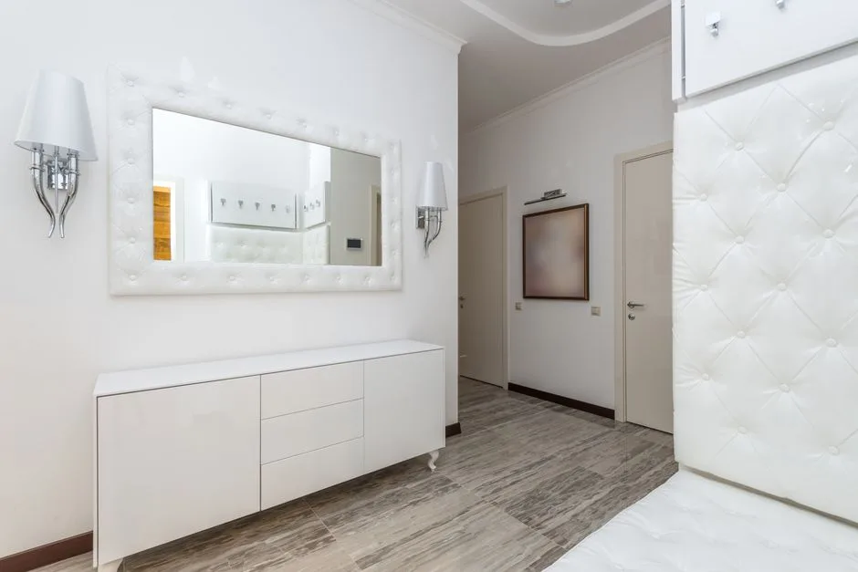 Stylish modern interior featuring white decor, a large wall mirror, and contemporary furnishings.