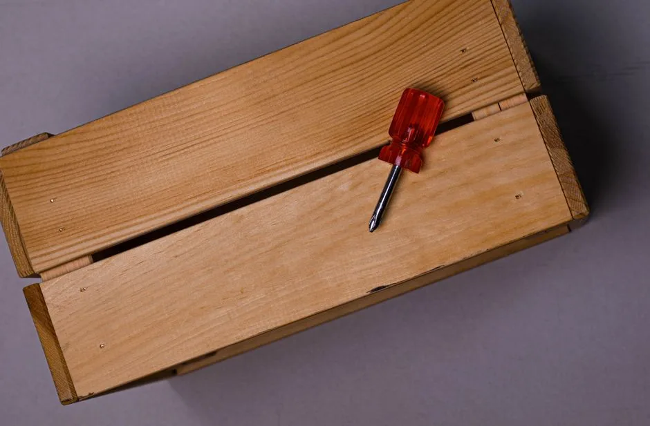 A minimalist image of a wooden box with a red-handled screwdriver, perfect for DIY themes.