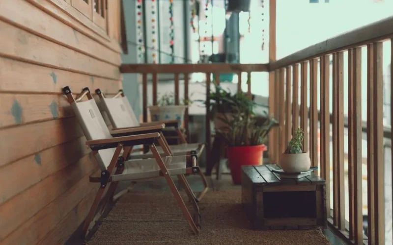 A charming balcony in Dalat, Vietnam featuring wooden chairs and lush plants, offering a relaxing retreat.