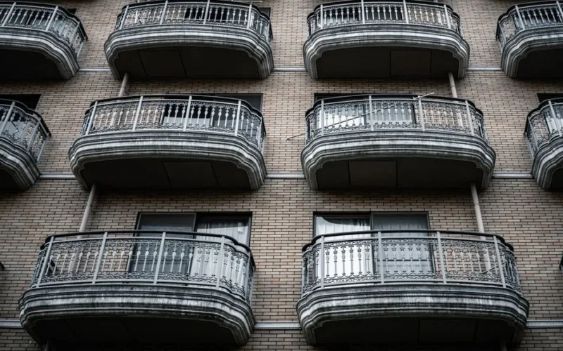 Symmetrical view of ornate balconies on a brick apartment building facade.