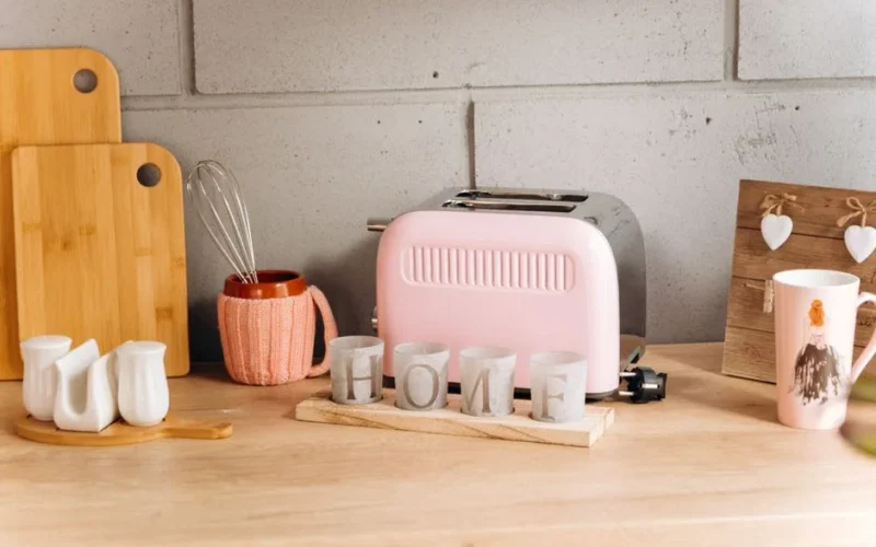Charming kitchen counter featuring a pink toaster, wooden decor, and cozy accessories.