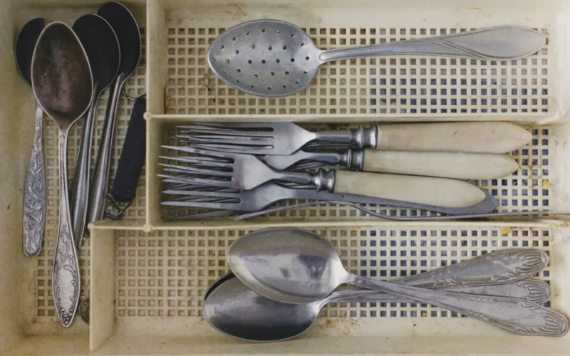 A collection of vintage silverware in an old cutlery tray, showcasing forks, knives, and spoons.