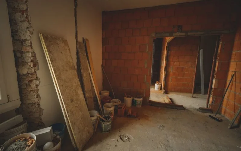 A red brick wall under construction with tools and materials scattered around in a renovation project.