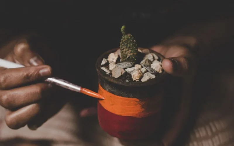 Artistic hand painting on a colorful cactus pot. Close-up view.