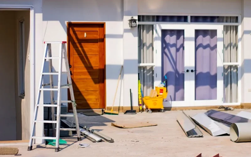 Front entrance of a house under renovation with tools and materials scattered around.