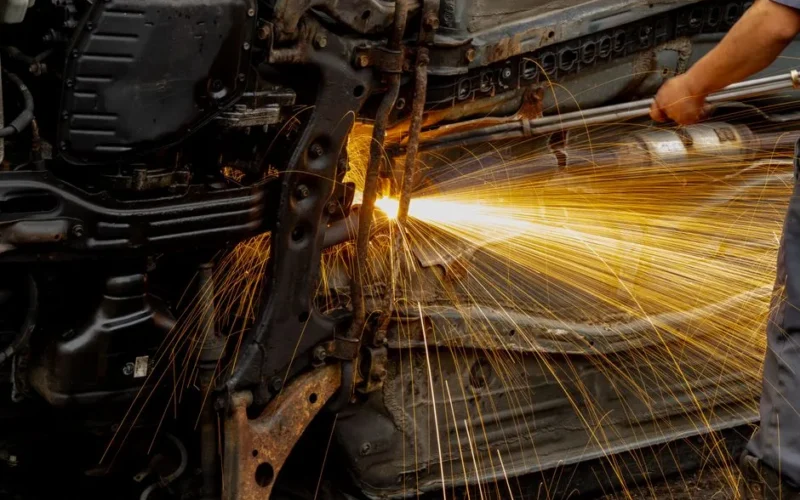 Mechanic welding car engine parts, with bright sparks flying. Hands-on automotive repair scene in workshop.