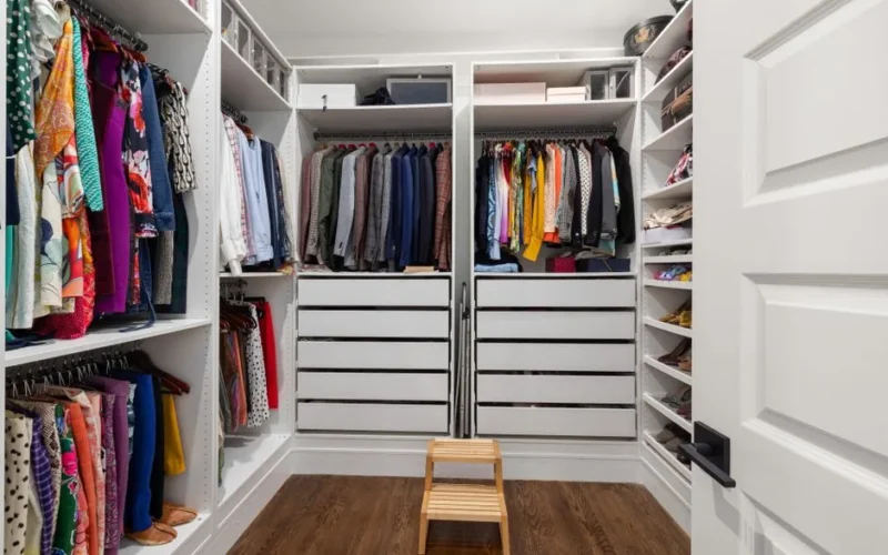 A neatly arranged walk-in closet showcasing a colorful variety of clothes and shoes.
