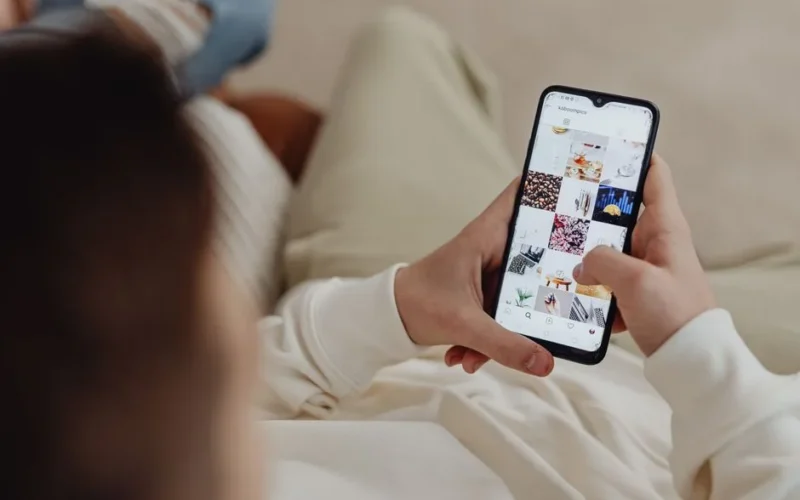 Person using smartphone to browse Instagram indoors, showing social media engagement.