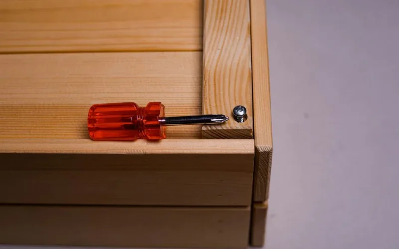 A detailed shot of a screwdriver inserted into a screw on a wooden box. Ideal for DIY themes.