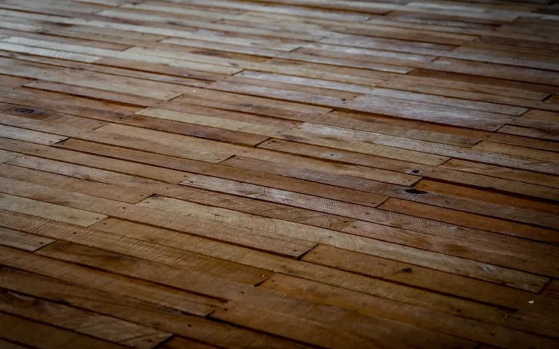 Detailed view of rustic wooden floor with staggered planks showcasing natural texture.