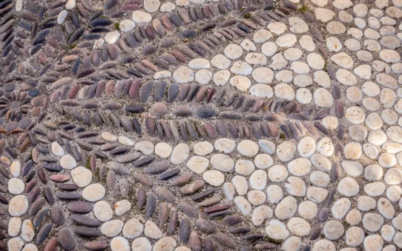 Detailed view of a stone mosaic pathway with artistic patterns using smooth pebbles.
