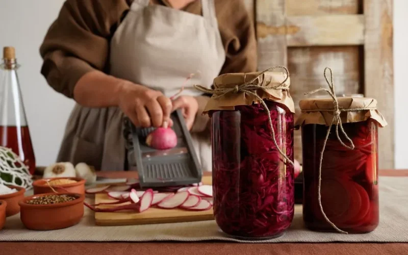Woman preparing pickled radishes in a rustic kitchen. Ideal for culinary and DIY themes.