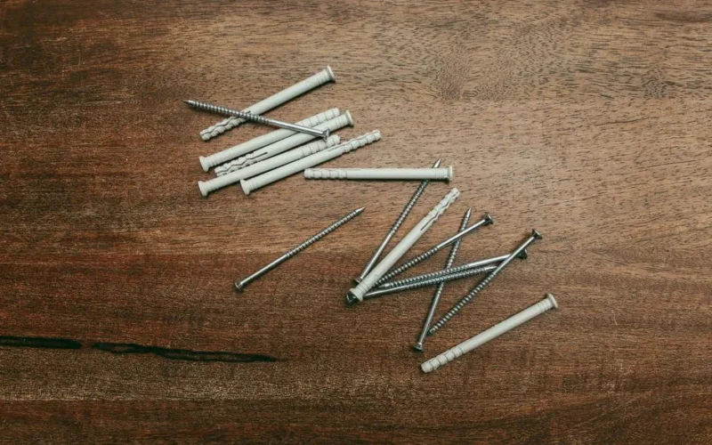 Close-up of screws and nylon anchors laid on a wooden background.