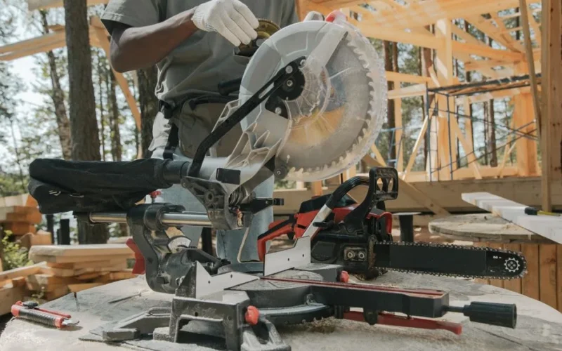 Close-up of a worker using a circular saw amidst forest construction. Manual craftsmanship at its best.