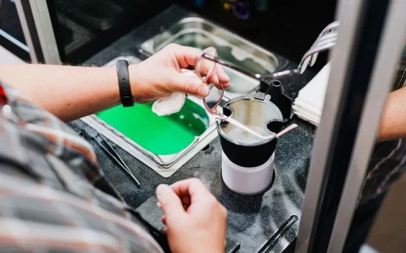 Detailed view of hands cleaning eyeglasses over a sink, showcasing precision and care.
