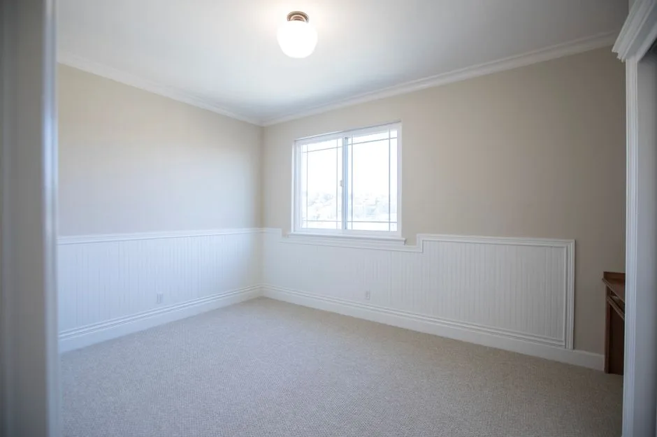A bright, empty room with minimalist design and a window providing natural light.