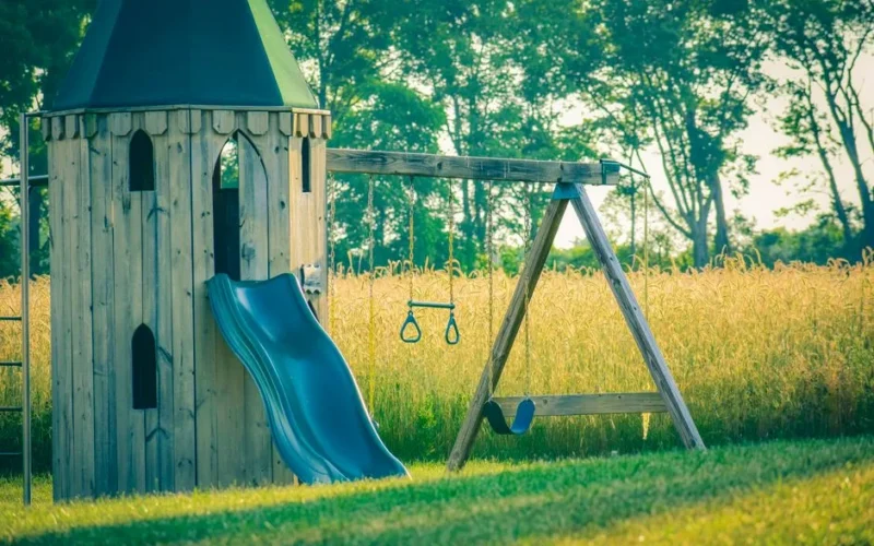 Timber tower with sway and chute near meadow with trees and lush verdant grass