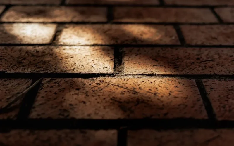 Detailed close-up of textured brick pavement with shadow play highlighting urban patterns.