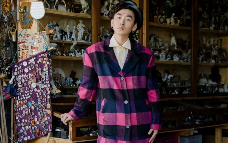 Stylish Asian man wearing a colorful coat at a vintage flea market.
