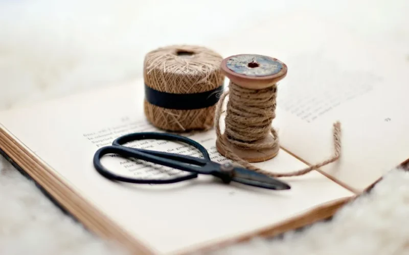 Close-up of scissors and twine on a vintage book, ideal for crafting inspiration.