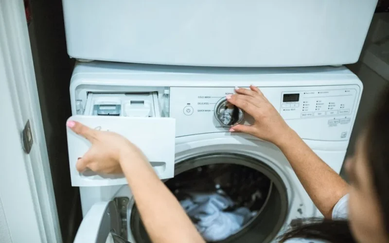 A person in a laundry room adjusting settings on a washing machine.