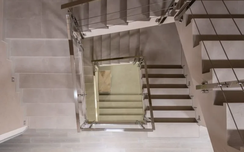 Top view flights of stairs with metal handrails and fencing located in light modern spacious multistory building with laminate floor
