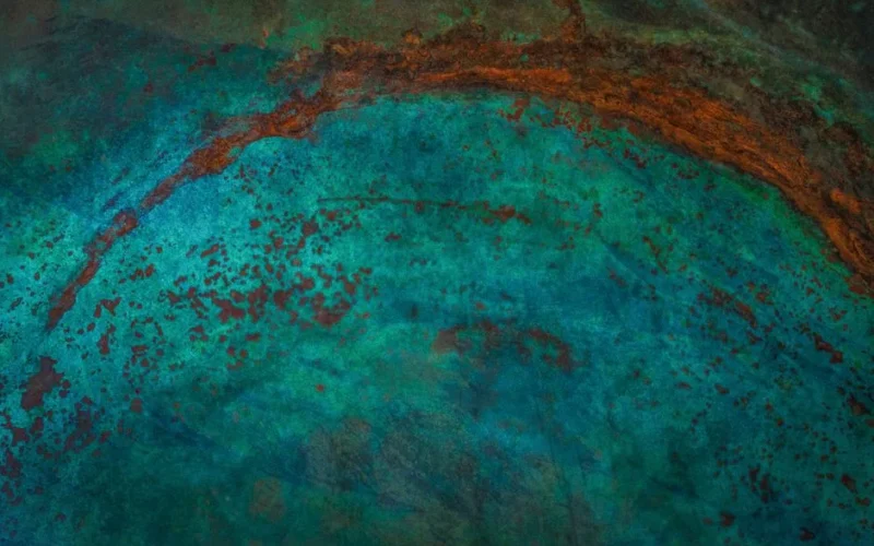 Close-up abstract of weathered metal surface with turquoise patina and rust details.