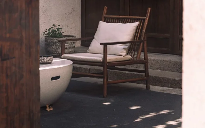 A serene outdoor patio arrangement featuring a wooden chair and a round table under natural light.