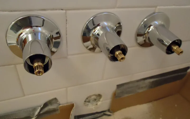 Here the new Price Pfister valve stems have been added to the newly retiled wall (with new holes). I do not tighten them yet to give some play, since the tub downspout has not yet been added to the lower hole. Background: This is image 16 of a repair project to fix a shower/tub diverter valve made by Barber Wilsons & Co Ltd. The handle which was supposed to divert water to the shower but it did not work; a plastic piece inside was broken. Unfortunately, since this valve could not be fixed from the front, it required a major operation to open up the back and replace pipes. I ended up replacing the defective valve with a Price Pfister valve-set so in future repairs will be easy.