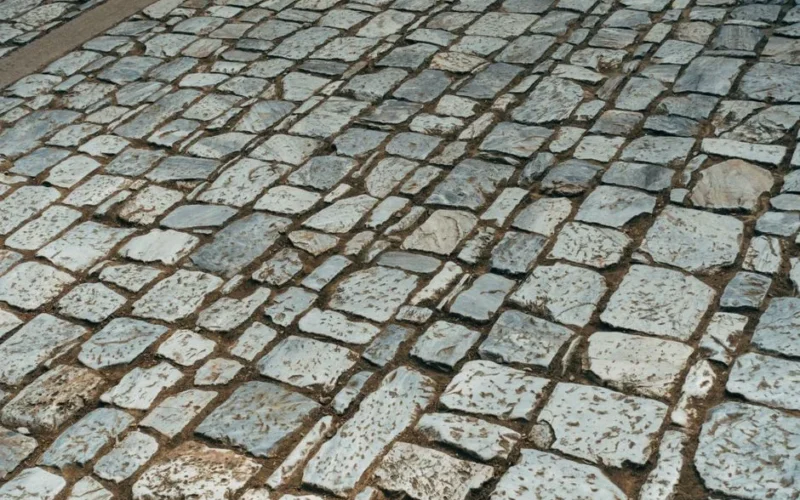 Old cobblestone path featuring granite stones in a classic pattern, offering a textured surface view.