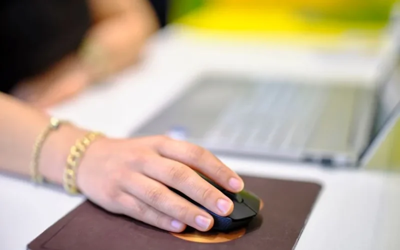 A person using a wireless mouse at a desk, perfect for business or technology themes.