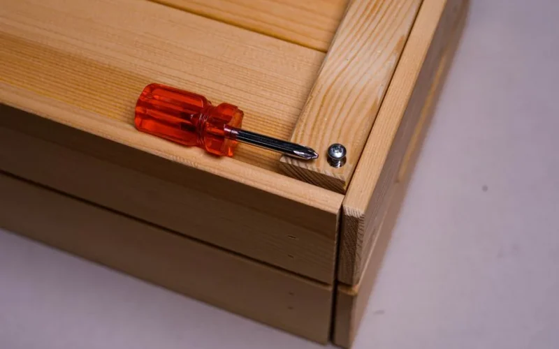 Detailed shot of a screwdriver and screw on wood, showcasing tool precision.