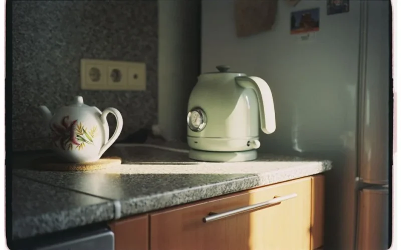 Sunlit kitchen counter with floral teapot and retro kettle, cozy ambiance.